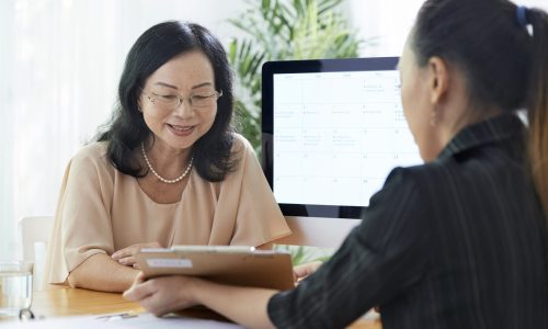 Senior Asian woman talking to insurance agent in office